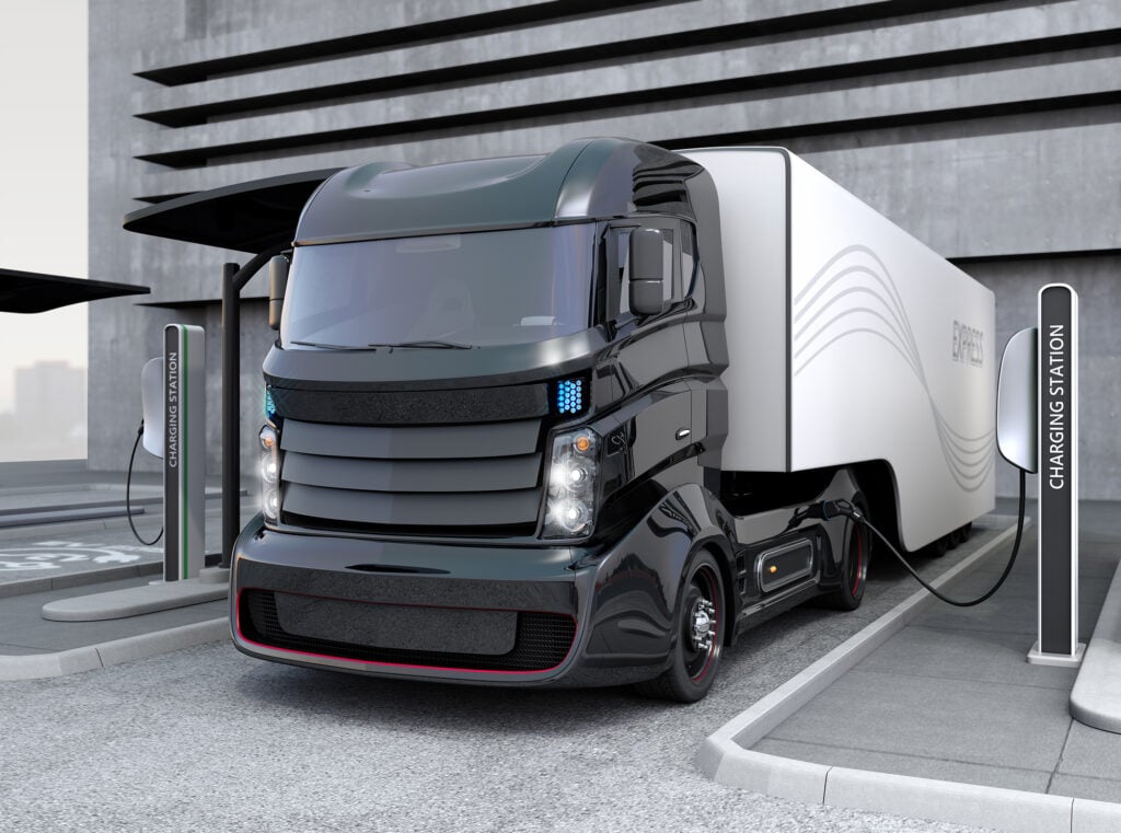 Hybrid electric truck being charging at charging station. Image via Chesky_W/Getty Images.